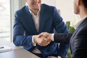 Men shaking hands, man in blue uses the proper etiquette 