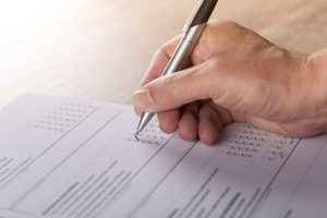 Person taking survey with silver pen filling in a bubble