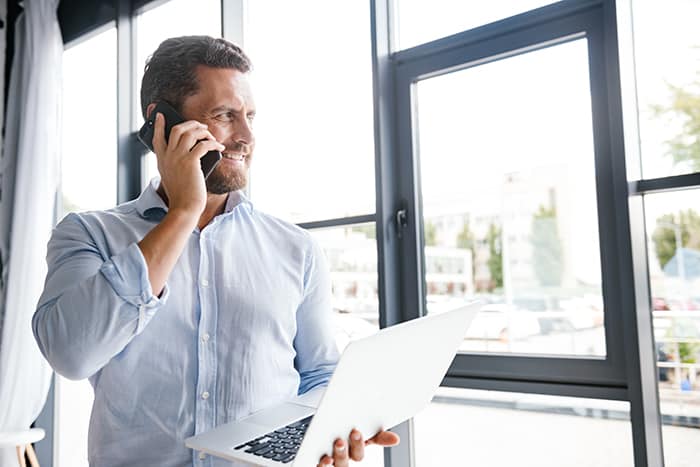 man using business phone system smiling out window