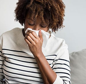 Black female coughs into tissue