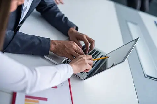 a consultant meeting with a business owner and looking at data on a computer