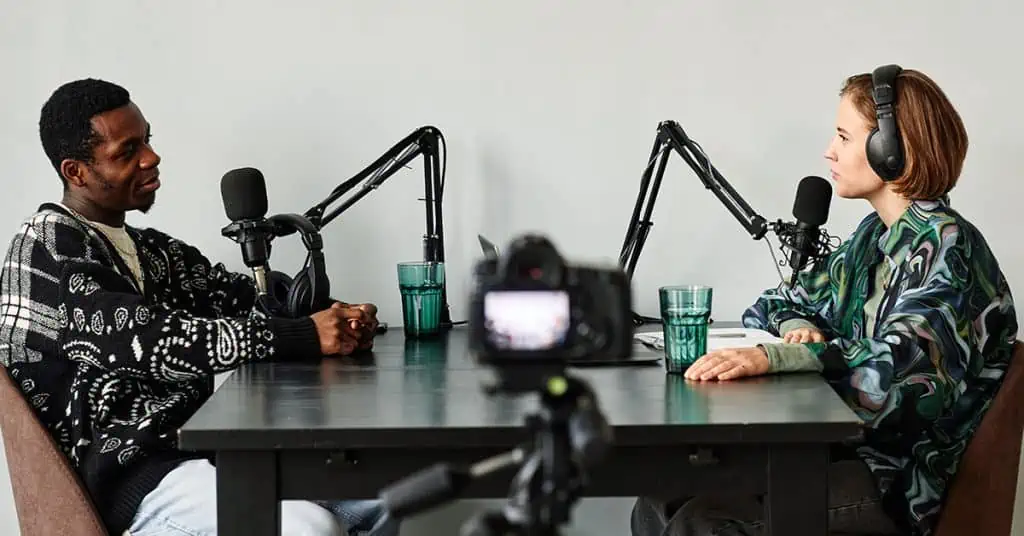 two men starting a business podcast by recording their first podcast with microphones