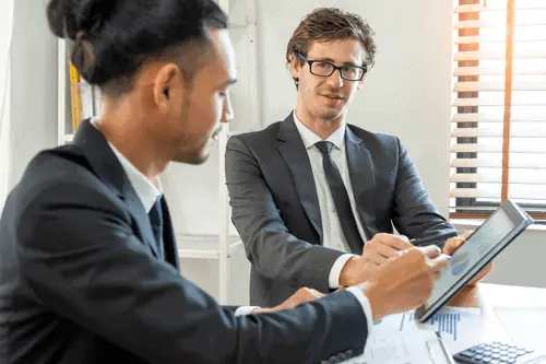 two businessmen looking at data on a tablet and talking about brand strategy AI 