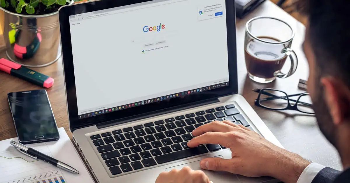 A person typing in the google search bar on a computer