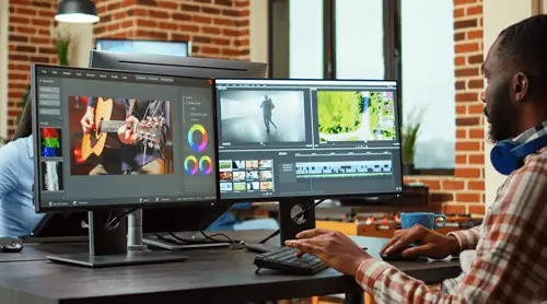 a man editing video on his computer screens to capitalize on the video marketing benefits