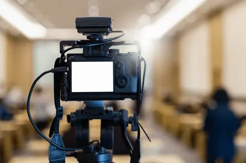 a camera pointing toward the front of a room to record a presentation 